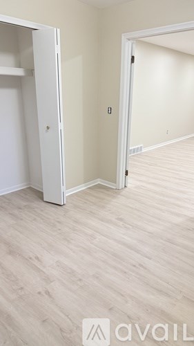 A room with a white door and a wooden floor.