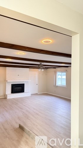 A living room with a fireplace and wooden floors.