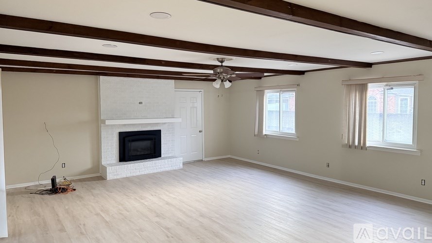 A spacious living room with a fireplace and a ceiling fan.
