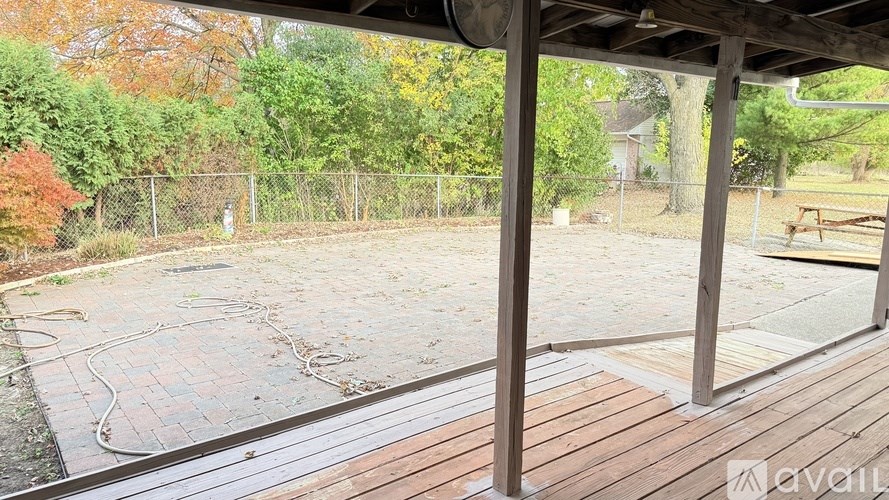 A wooden deck with a bench and a fence in the background.
