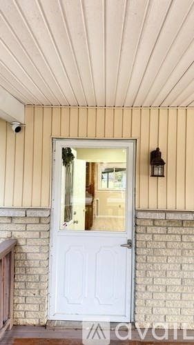 A white door with a glass window is set in a brick wall.