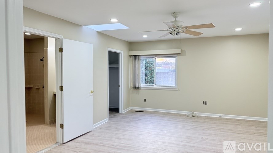 A room with a ceiling fan and a window with a view of trees.