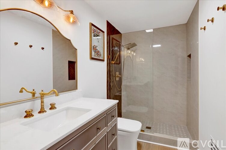 A bathroom with a white sink and gold fixtures.