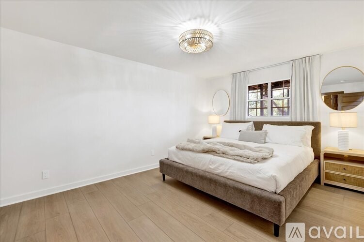 A bedroom with a large bed and a round mirror on the wall.
