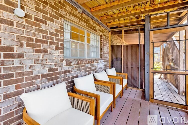 A wooden deck with two chairs and a brick wall.