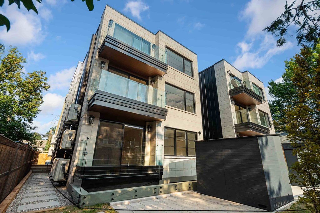 A modern two-story house with a black fence and glass balconies.