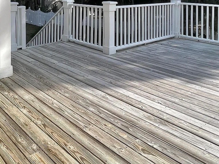 A wooden deck with a white railing.