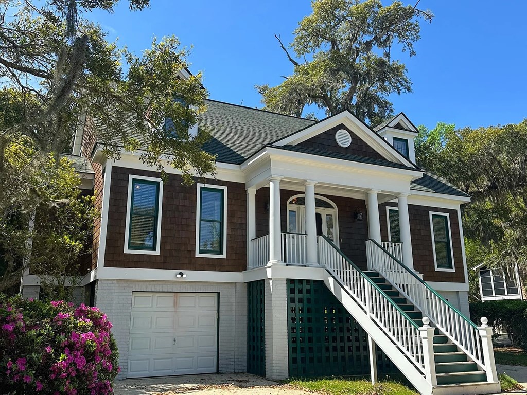 A two-story house with a white garage door and a green staircase railing.