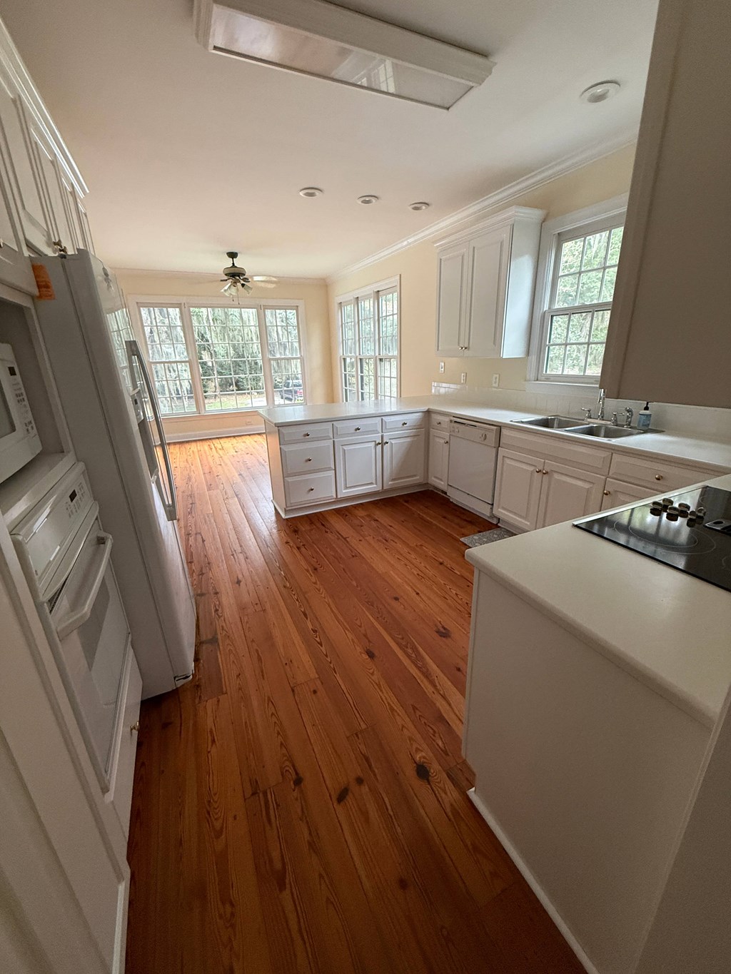 A kitchen with wooden floors and white appliances.