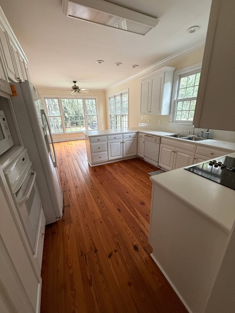 A kitchen with wooden floors and white appliances.