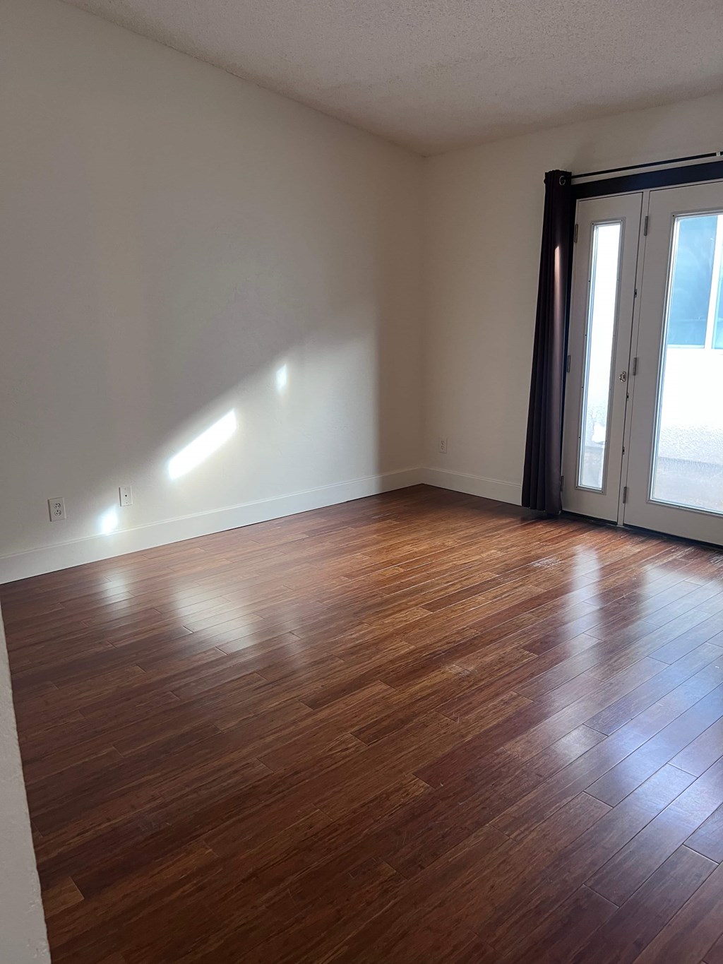 A room with wooden flooring and a sliding glass door.