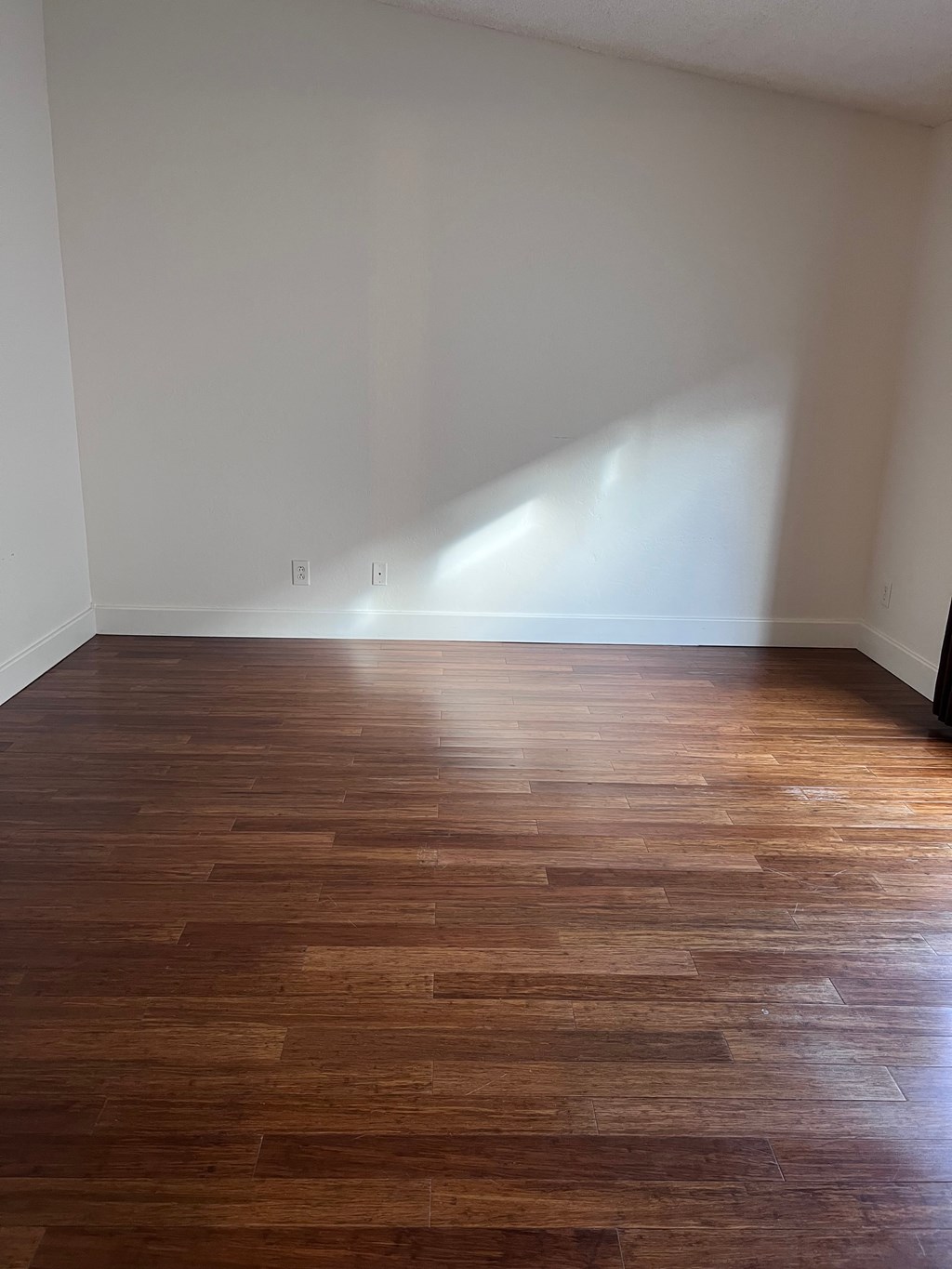 A room with wooden flooring and a white wall.