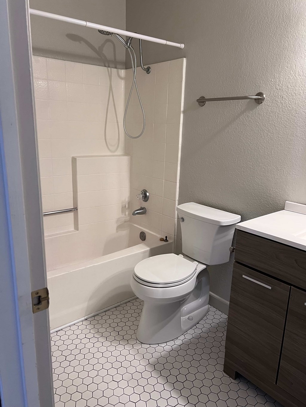 A white toilet sits in a bathroom with a white tiled floor and walls.