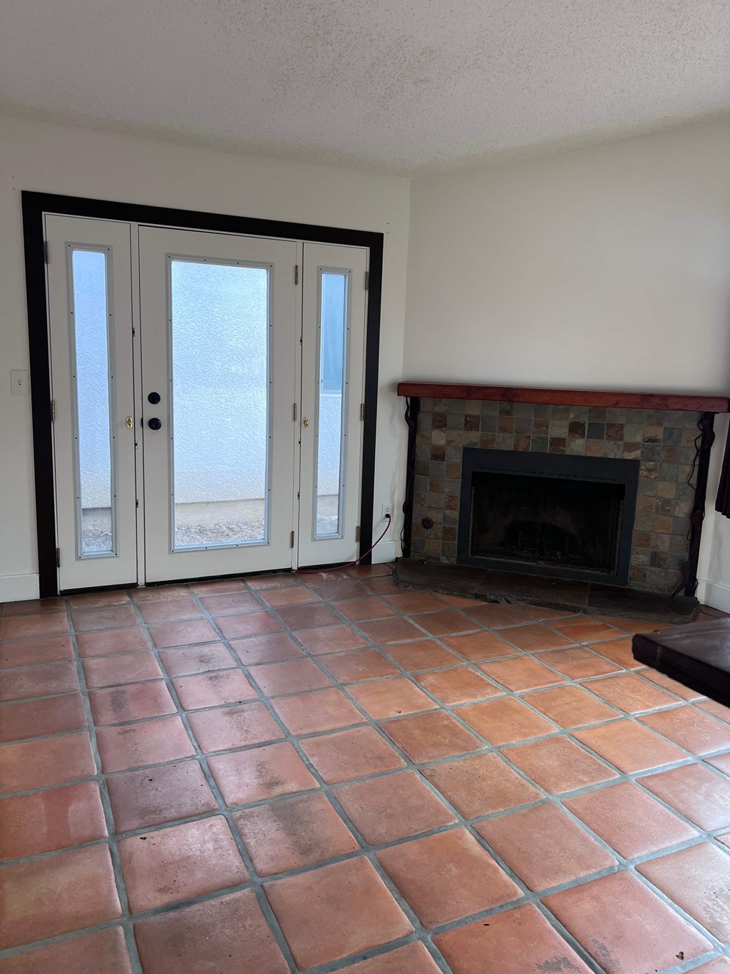 A room with a fireplace and tiled flooring.