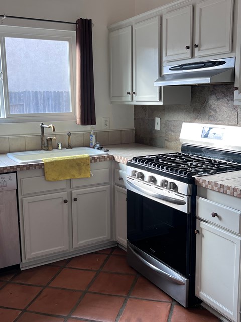 A kitchen with a black stove top oven and white cabinets.