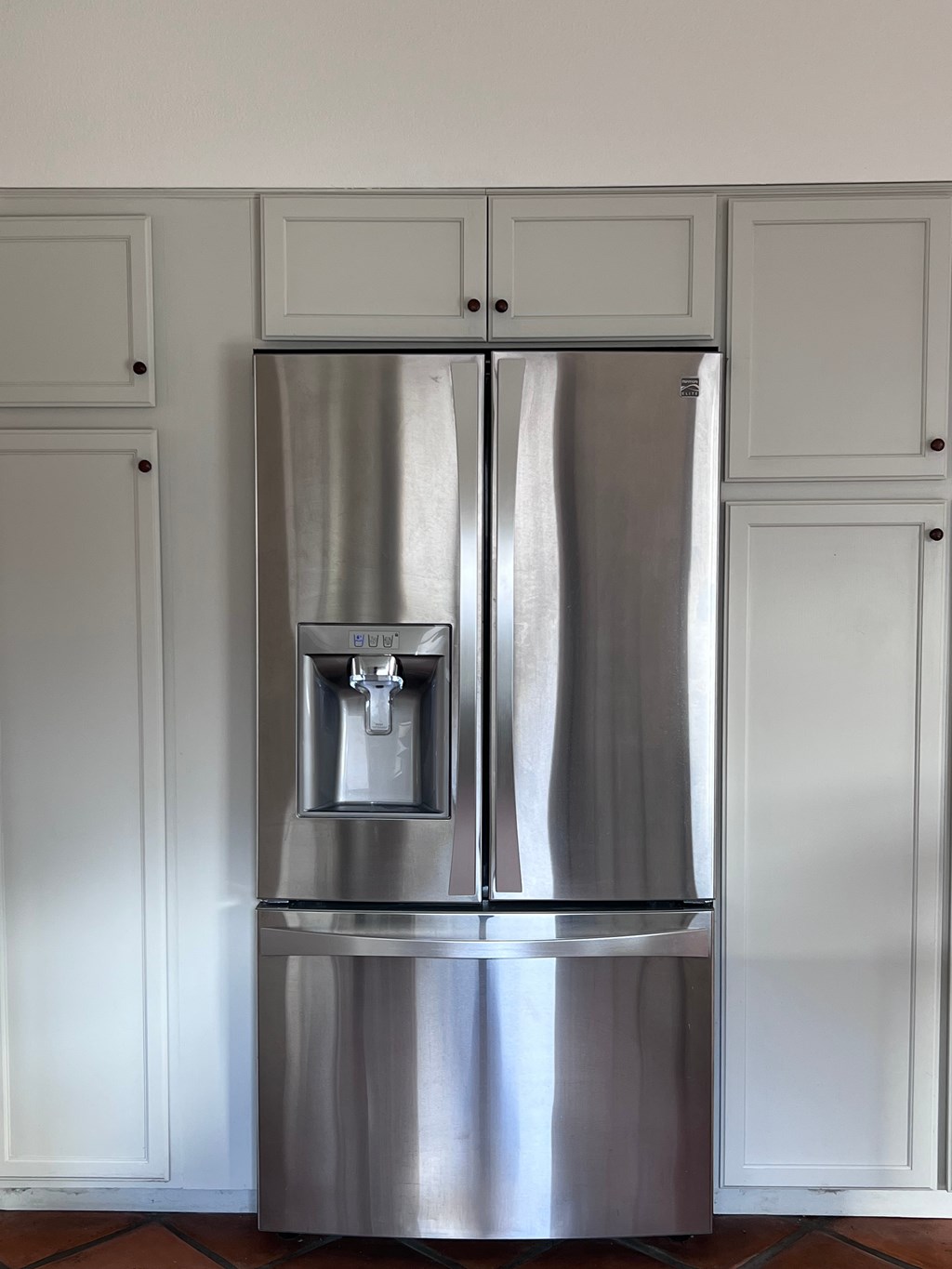 A stainless steel refrigerator with a water dispenser in the middle.