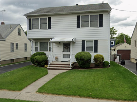 A white house with a grey roof and a green lawn.