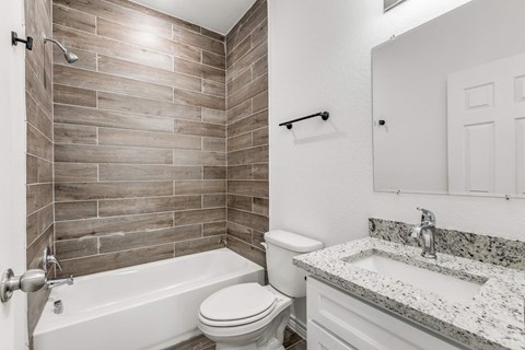 A bathroom with a white tub, toilet, and sink.