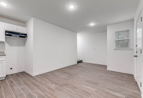 A spacious room with wooden flooring and white walls.