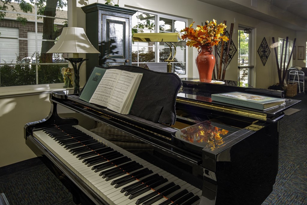 A black piano with a sheet of music on top of it.