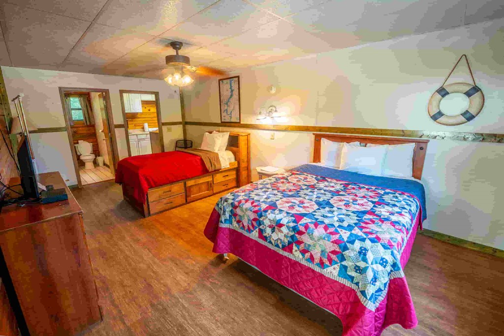 A bedroom with a bed covered in a pink and blue quilt.