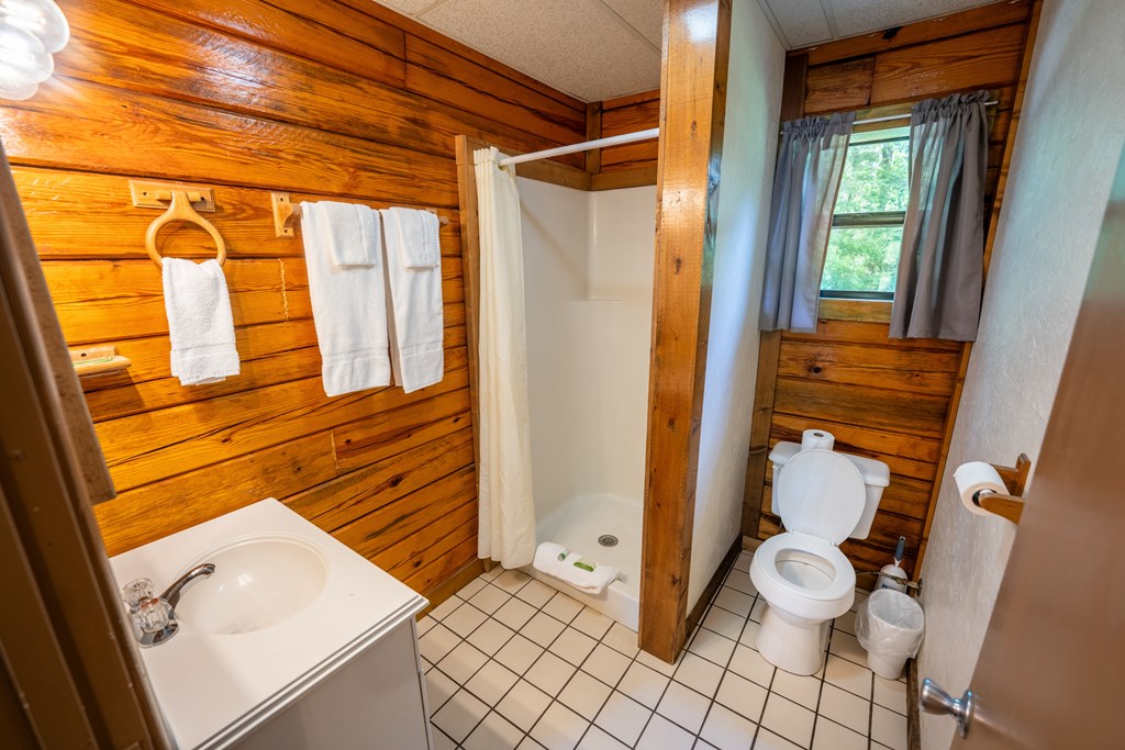 A bathroom with a wooden wall and white fixtures.