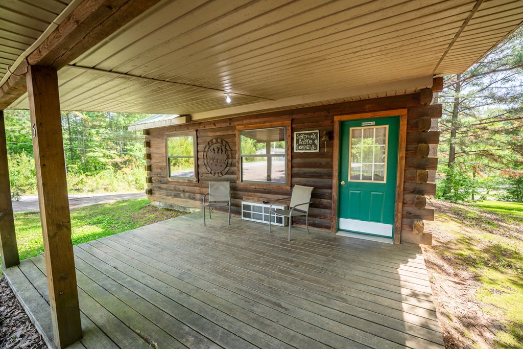 A wooden porch with a green door and a white window.