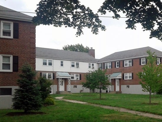 A white building with a green roof is surrounded by trees.