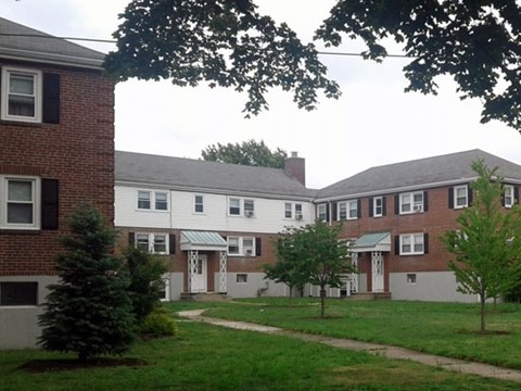 A white building with a green roof is surrounded by trees.