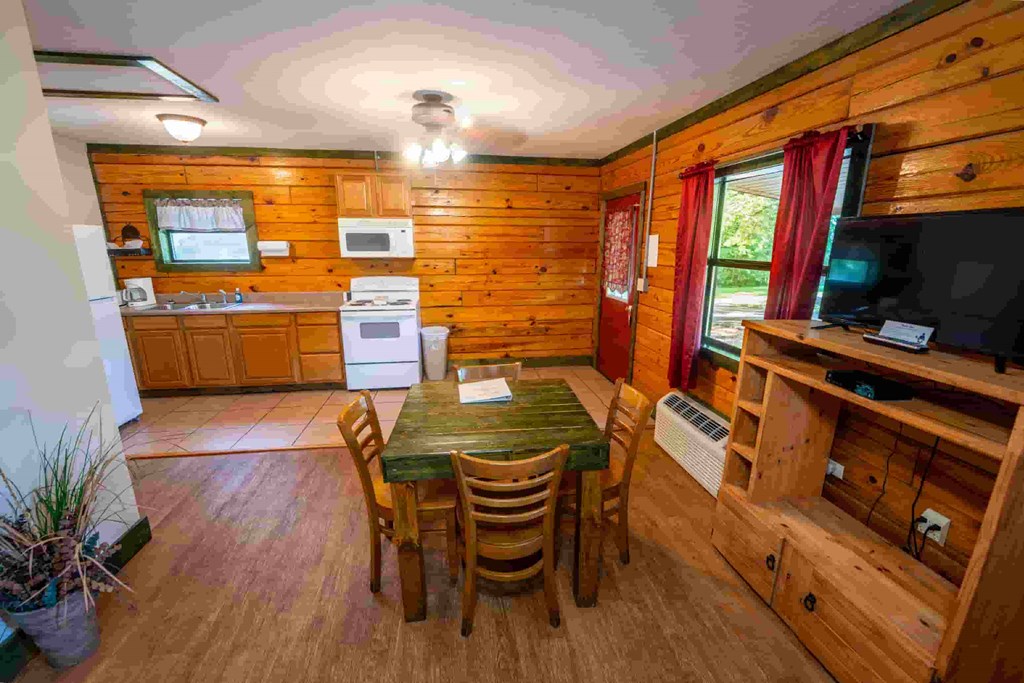 A wooden cabin with a table and chairs in the middle of the room.