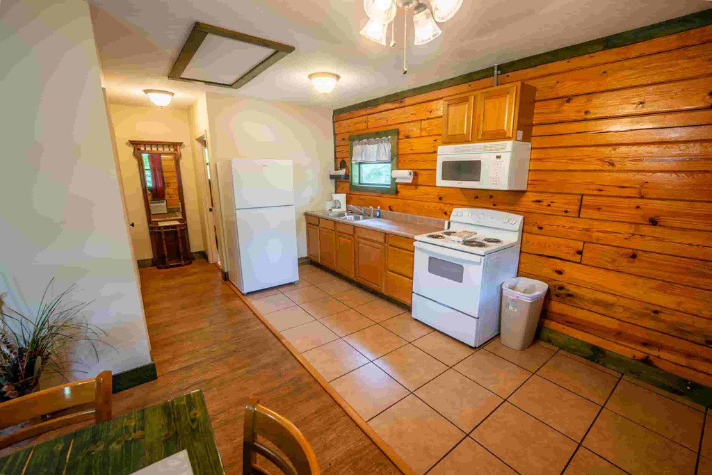 A kitchen with wooden walls and a white fridge.