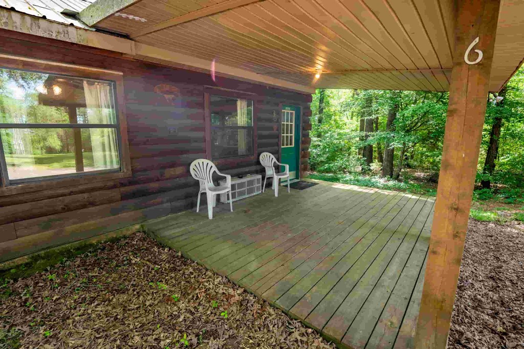 A wooden deck with two chairs and a table is in front of a house.
