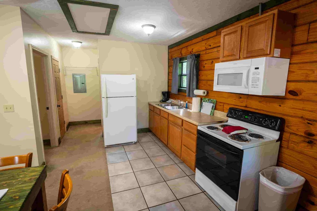 A kitchen with a white fridge, white stove, and a white microwave.