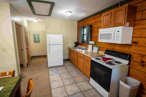 A kitchen with a white fridge, white stove, and a white microwave.