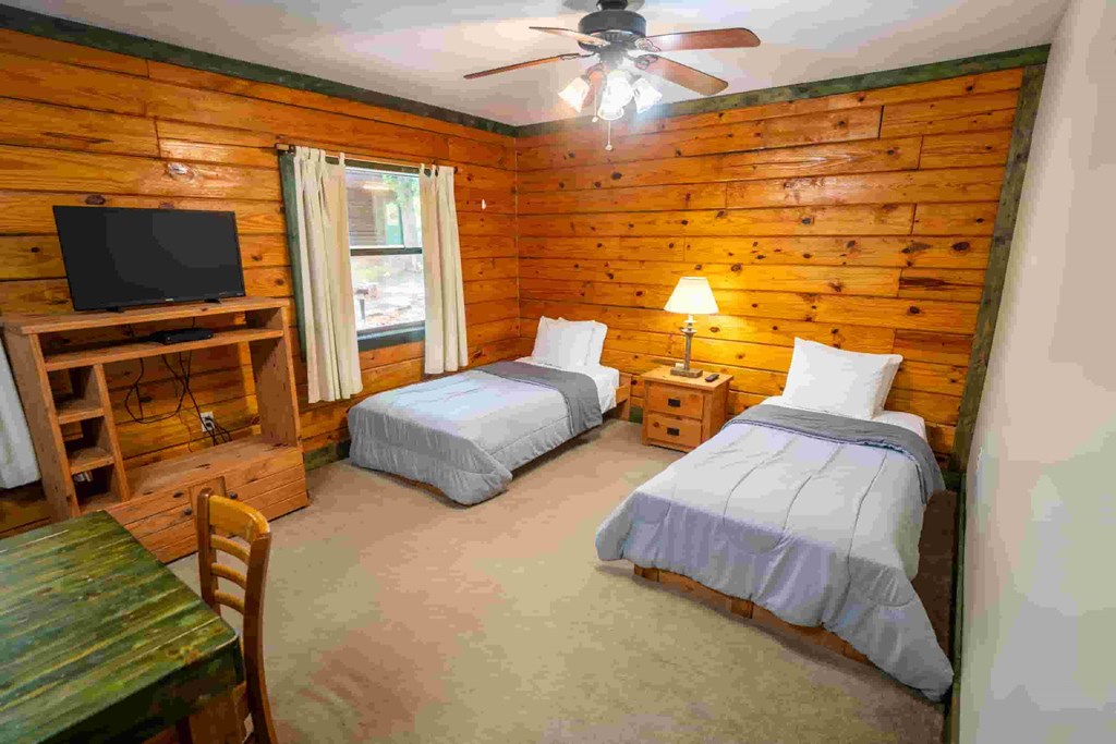 A room with two beds, a table, and a television.