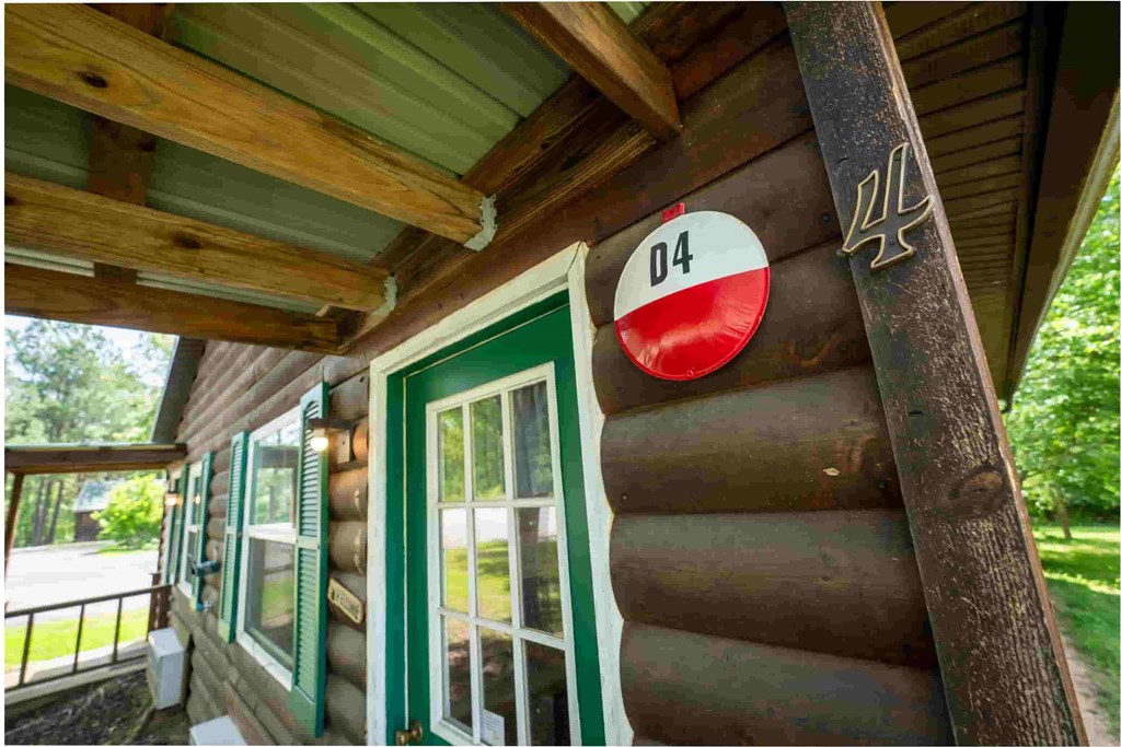 A wooden building with a green door and a sign that says 04.