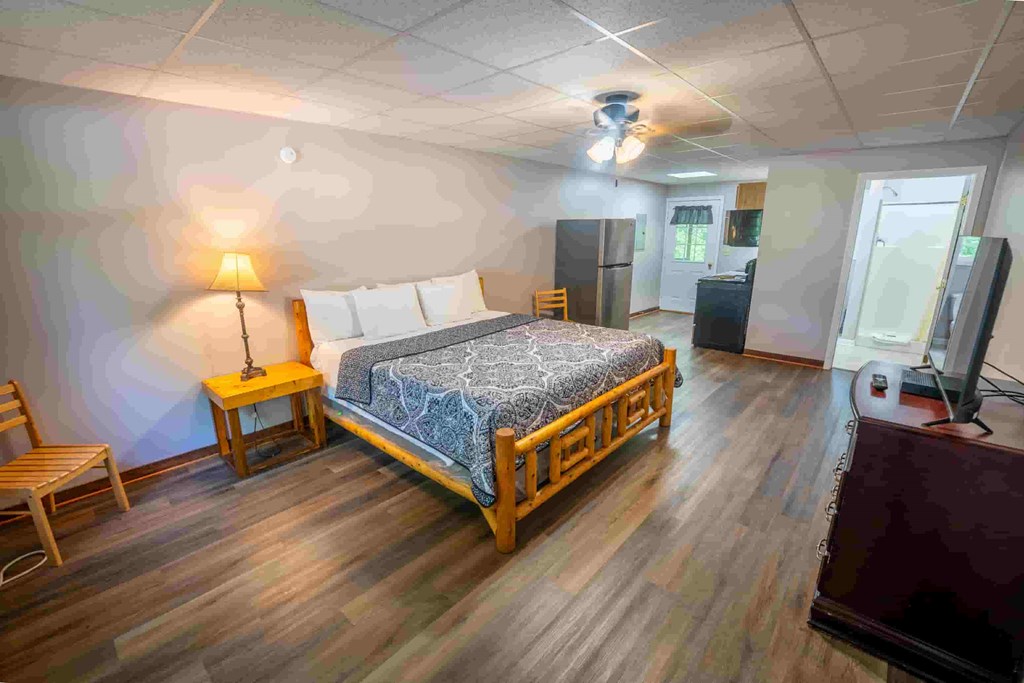 A bedroom with a bed, chair, and lamp.