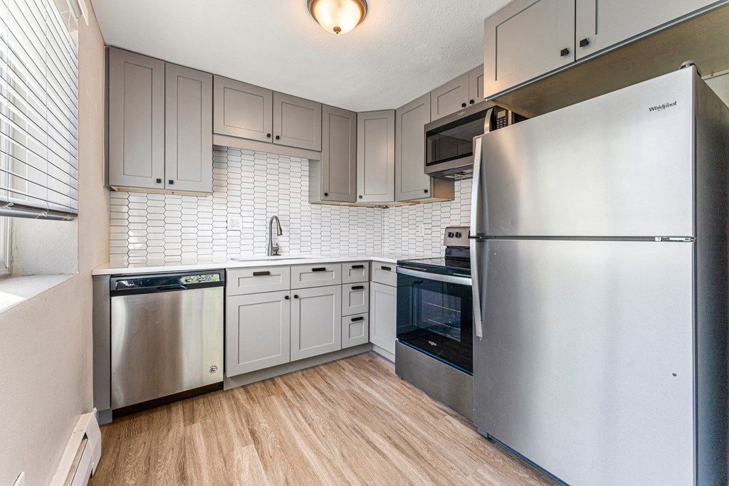 A kitchen with a refrigerator, dishwasher, and oven.