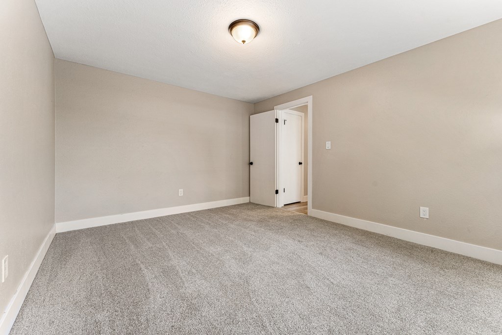 A room with a carpeted floor and a door.