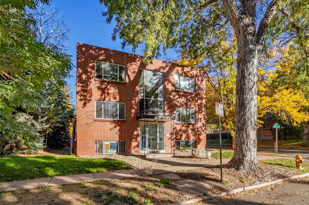 A red brick building with a tree in front of it.