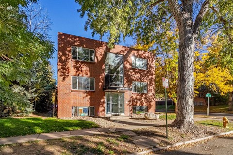 A red brick building with a tree in front of it.