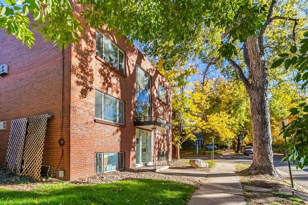 A red brick building with a tree in front of it.
