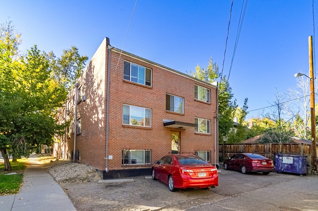 A red car is parked in front of a brick building.