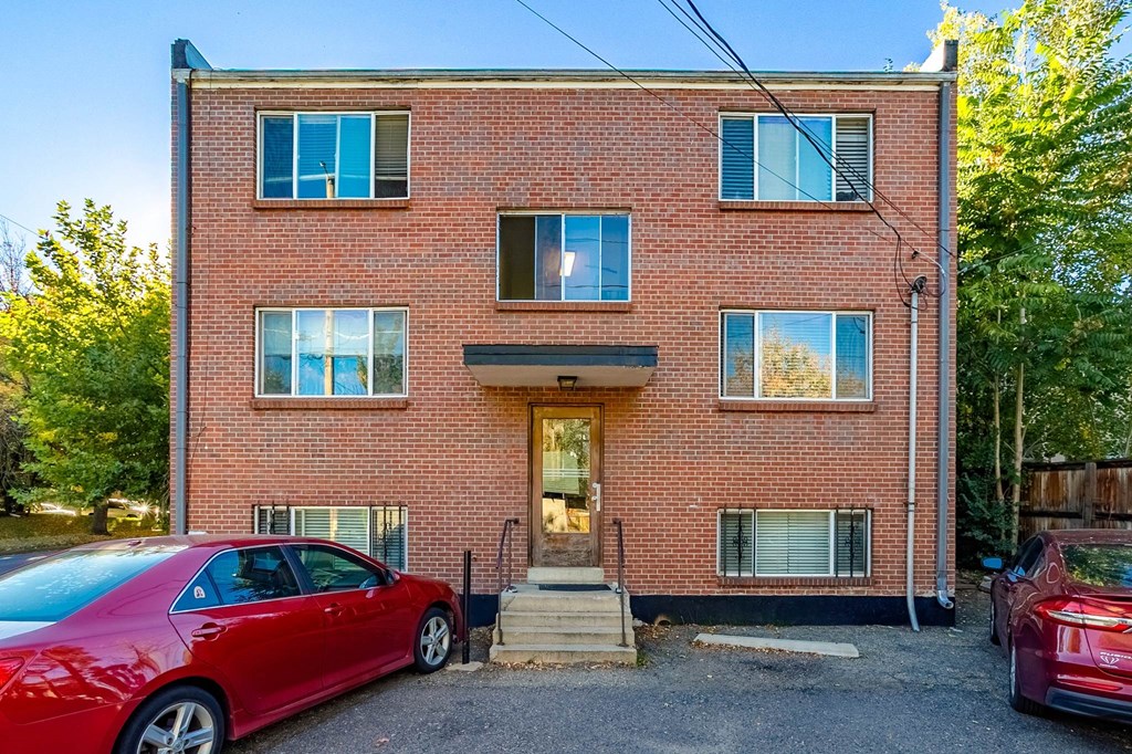 A red car is parked in front of a brick building.