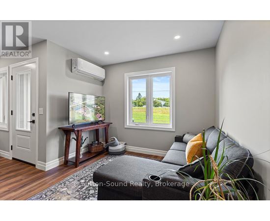 A living room with a grey couch and a window showing a view of a field.