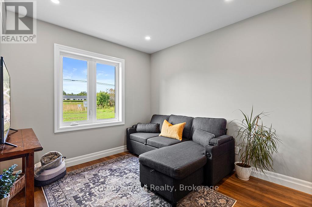 A living room with a grey couch and a window showing a view of a field.