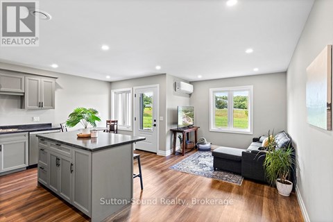A living room with a grey couch and a window showing a view of a field.