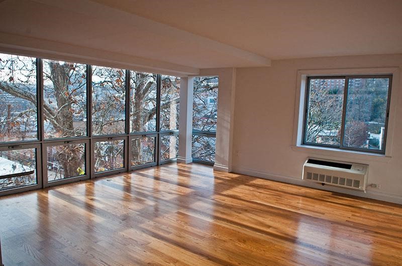 an empty living room with a wood floor and large windows