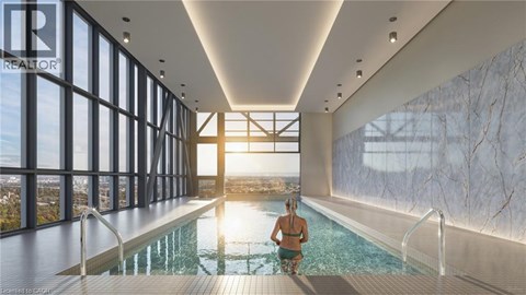 A woman is sitting in a pool in a large room with a marble wall.
