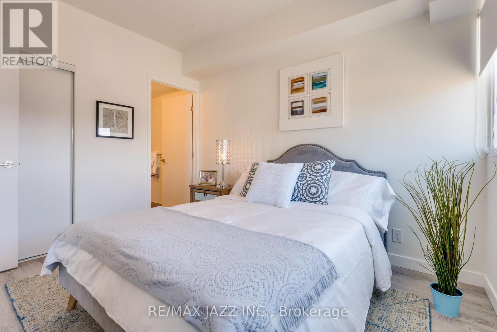 A bedroom with a large bed and a potted plant.